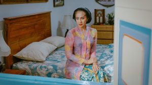 Bu Broto duduk merenung sendirian di kamar dalam film Losmen Bu Broto